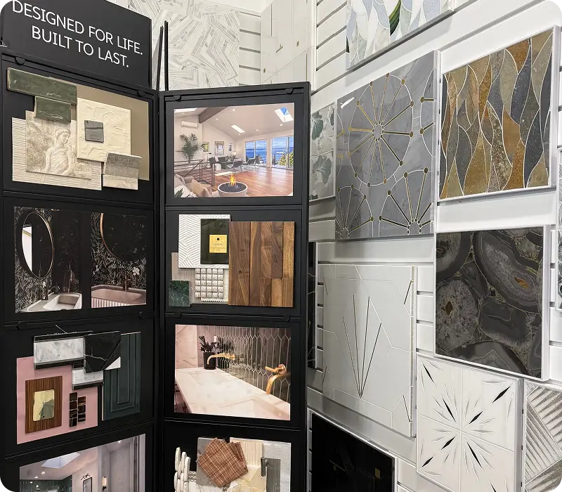 A display board in a design showroom featuring various tile samples, decorative wall panels, and photographs of finished interior spaces.