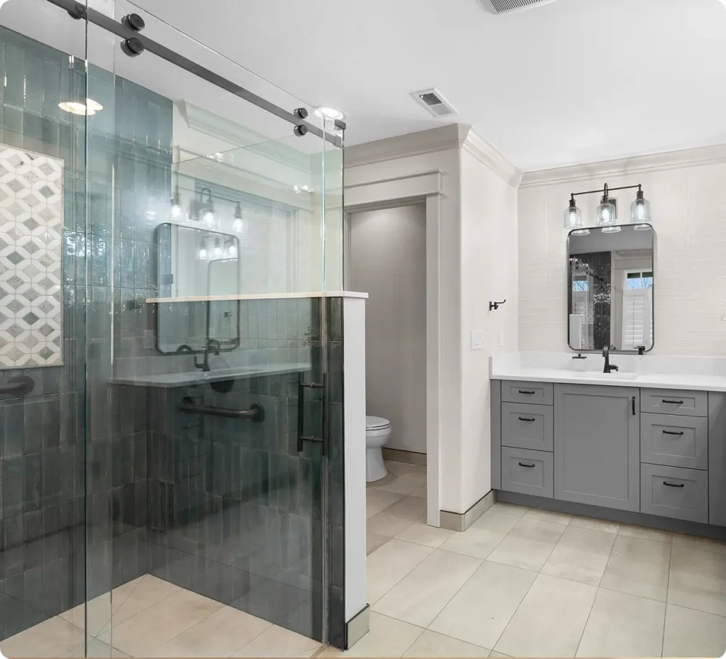 Modern bathroom with a glass shower, gray tile walls, and a double-sink vanity—perfect for Aging in Place Remodeling in the Greater Seattle Area. Neutral tones and clean design elements throughout.